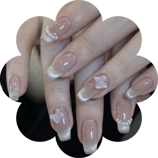 Elegant short coffin ballerina shape press on nails with a mesmerising cat eye finish, adorned with delicate butterfly and pearls accents for a luxurious nail art look.