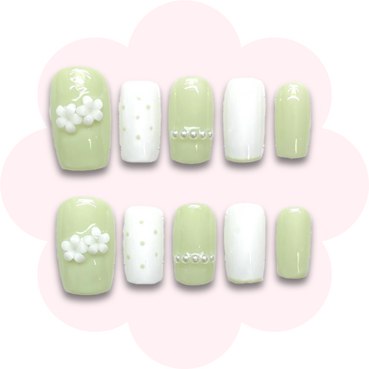 cute long lasting reusable press on nails featuring small flower embellishments and pearl accents on a light green base. 