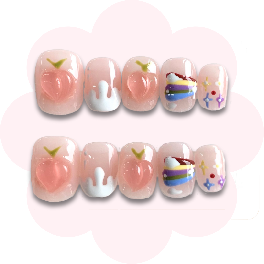 super short press on nail featuring peaches and rainbow accents on a peachy pink base color. 